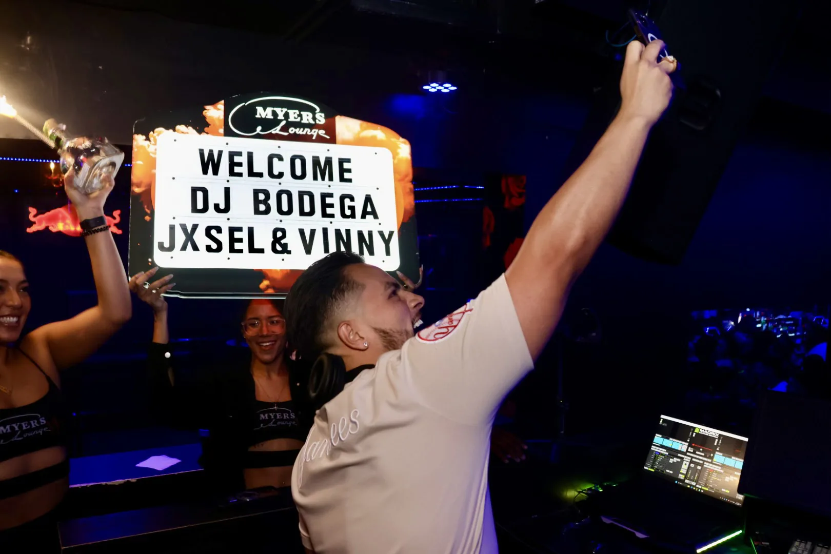 Guests holding a welcome DJ Bodega sign in a club